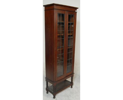 A early 20th century antique oak display cabinet having twin lattice doors opening to reveal adjustable shelving. Raised on t