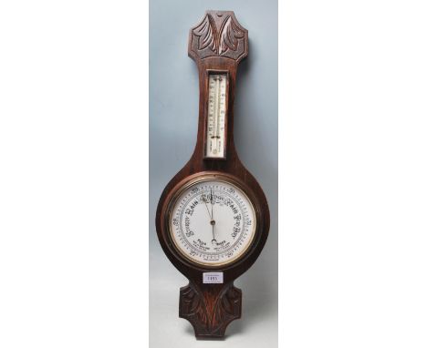 An early 20th century Made in England oak wall barometer. The heavy banjo barometer having silvered dial and thermometer with