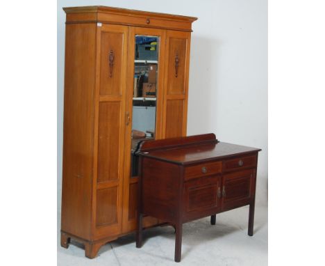 An early 20th century Edwardian oak single wardrobe having a flared pediment top over a mirrored door raised on bracket feet 