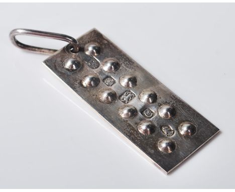 A 1977 silver ingot pendant and rectangular form having raised roundell decoration and pendant bale to the top. Hallmarked fo