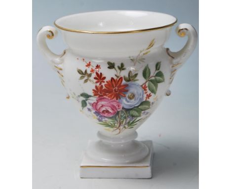 A Royal Worcester porcelain twin handled small vase urn with white ground having chintz foliate spray design. The underside w