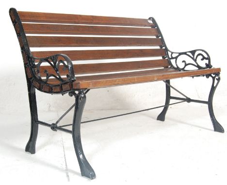 A late 20th Century Victorian style garden bench having wooden slats and shaped foliate bench ends united by a single stretch