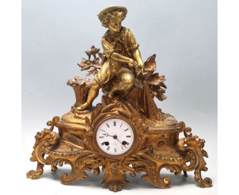 An early 20th Century French Rococo Revival gilt and spelter mantel / mantle clock depicting a young boy atop a naturalistic 