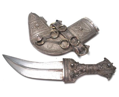 An early 20th Century Islamic white metal curved dagger / jambiya having a short curved blade with a central ridge which is s