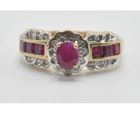 A hallmarked 9ct gold ring being set with rubies and diamonds having one central oval cut ruby flanked by six square cut red 