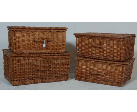 A collection of 4 vintage wicker baskets each having a hinged lid to the top with leather straps opening to reveal a spacious