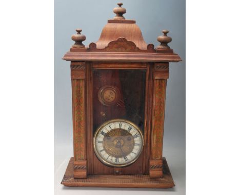 A vintage antique style wall clock having a pediment top over a glazed door with a brass and white enamel clock face The cloc