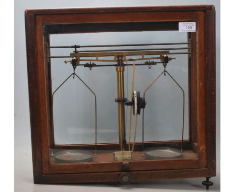 A pair of mid century wooden cased scientific scales in brass set to a black glass base with adjustable feet. The base marked