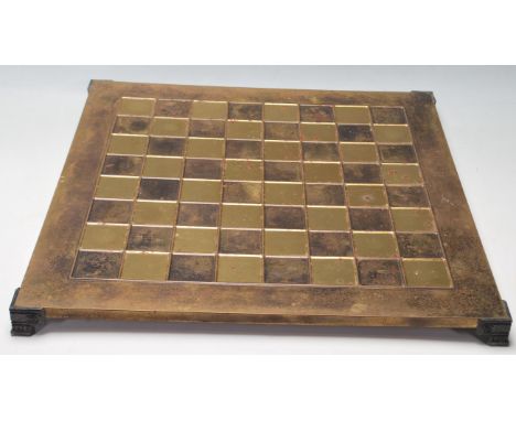 A 20th Century brass chess board raised on bracket feet with ebonised squares together complete with cast brass chess pieces 