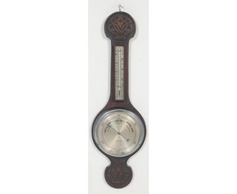 An early 20th century carved oak aneroid wall barometer. The barometer of banjo form having central dial with thermometer to 