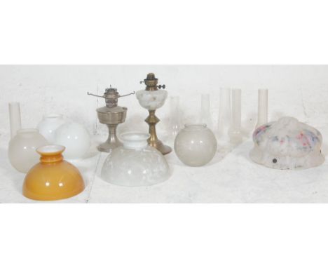 A good collection of 20th century antique oil lamp parts to include milk glass spherical shades, oil lamp glass funnels, crea