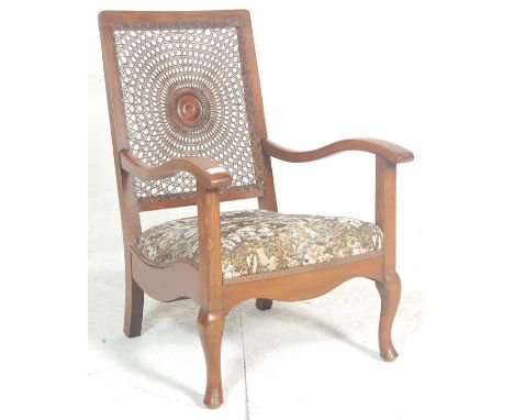 A 1930's Art Deco walnut bergere cane worked fireside armchair. Raised on cabriole legs with pad feet having a tapestry overs