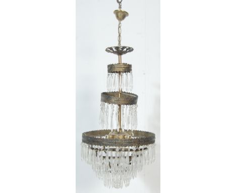 A large 20th century antique style glass and brass chandelier having crystal glass droplets hanging from a three graduated ci