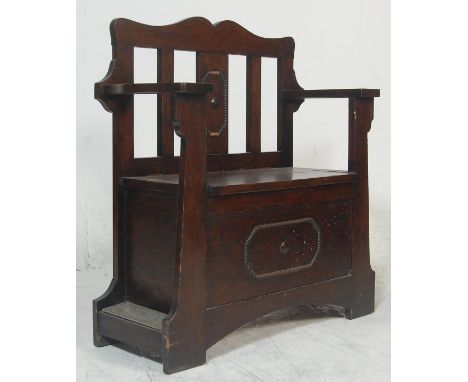 A 1920's carved oak Jacobean revival hall settle bench / stick stand combination. Raised on squared legs with a panelled wood