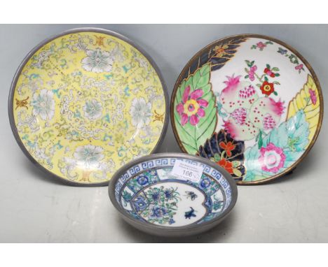 A collection of three mid 20th century Chinese pewter and ceramic plates. The collection comprises of a small dish having blu