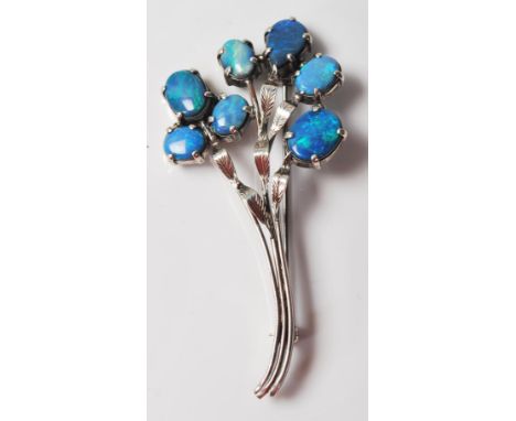 A mid 20th Century silver floral spray brooch being set with seven oval opal doublets in prong settings with applied and engr