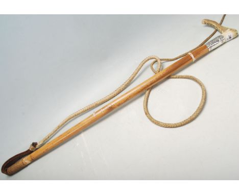 A 20th Century vintage whip having a wooden bone handle over a silver collar decorated with a crest and floral swirls over a 