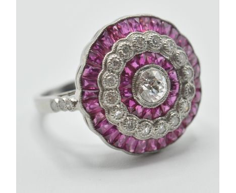 A platinum ruby and diamond cocktail ring. The ring having a round head with a central brilliant cut diamond with a halo of f