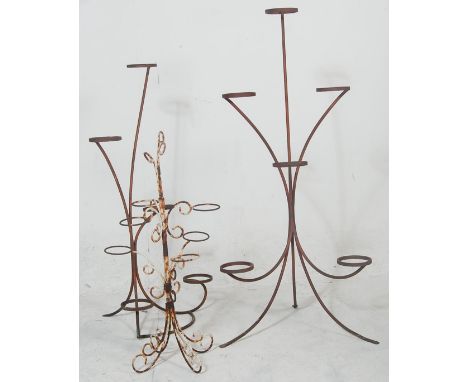 A pair of vintage 20th century retro blacksmith iron florist plant stands being made of metal band designed to hold five pots