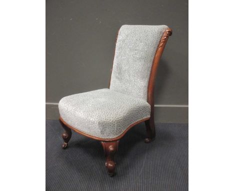 A mid Victorian carved walnut low chair on scroll feet and ceramic castors