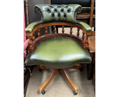 A captains chair with button back upholstery with a spindle back on a rotating base 