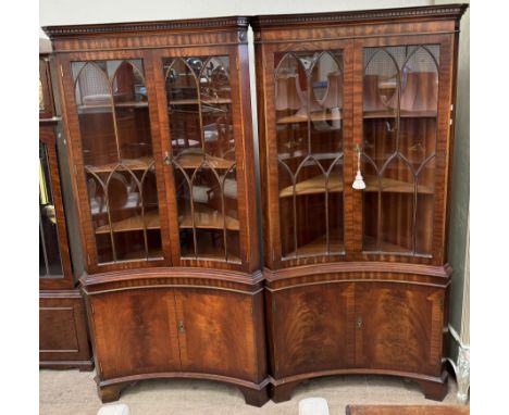 A pair of reproduction mahogany standing corner cupboards with a moulded dentil cornice above an inverted bowed front with a 