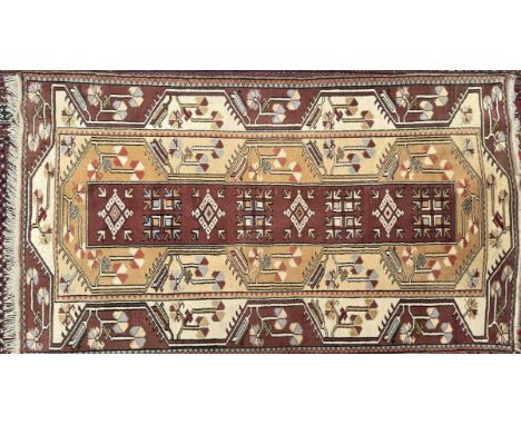 A rug with a light brown ground and geometric decoration, 116cm x 200cm