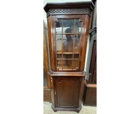 A reproduction mahogany corner cupboard with a moulded cornice and carved frieze with a glazed door and cupboard base on brac
