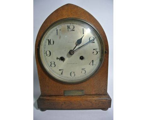 An oak mantle clock with lancet shaped case enclosing an eight day striking movement