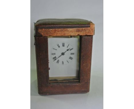 A brass carriage clock, the shaped case with enamelled dial and eight day timepiece set within a red Morocco travelling case