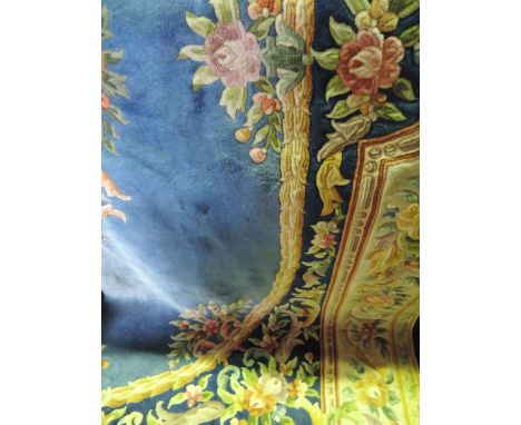 A substantial Chinese washed wool carpet, the oval mid blue ground field with floral panels set within deeper blue ground wor