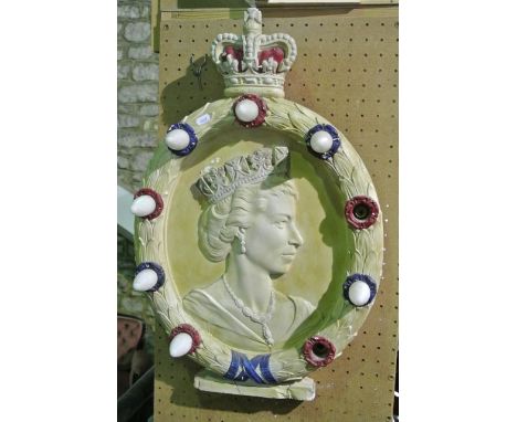 A circular plaster plaque commemorating Queen Elizabeth II with a laurel wreath swag with light fittings