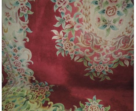 A heavy Chinese washed wool carpet with plum ground field, set within stylised floral borders
