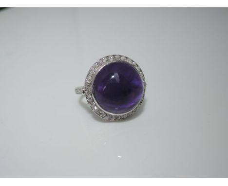 An amethyst and diamond dress ring, centred with a cabochon amethyst weighing approximately 13,50cts, the bezel and shank emb