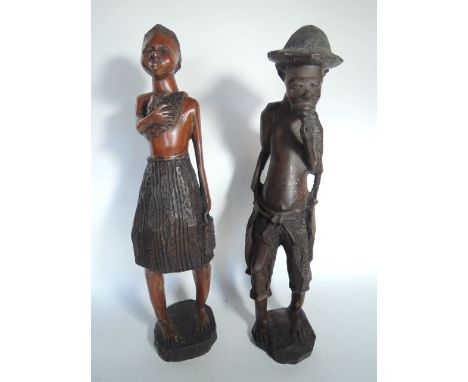 An African carved hardwood figure of a smoking/eating male in standing pose wearing a hat, 55 cm tall approx together with a 