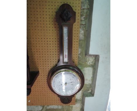 An aneroid barometer with silvered dial, the casework with applied and carved detail