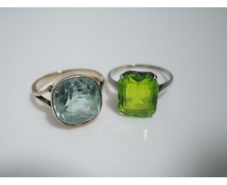 A blue stone ring, possibly aquamarine, in 9ct rose gold, size M 1/2; and a green stone ring, the central emerald-cut stone, 