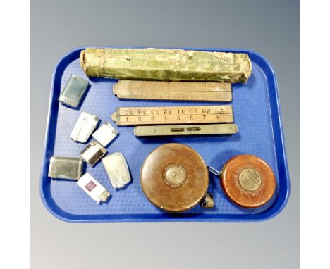 A tray of two vintage leather tape measures, spirit level, lighters, two folding wooden rules 