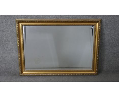 A large contemporary gilt framed mirror with repeating design bevelled plate. H.76 W.106 cm 