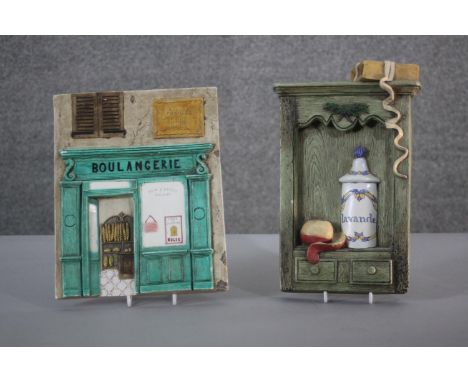 Two vintage relief hand painted ceramic plaques one modelled as the front of a French bakery the other as a kitchen dresser. 