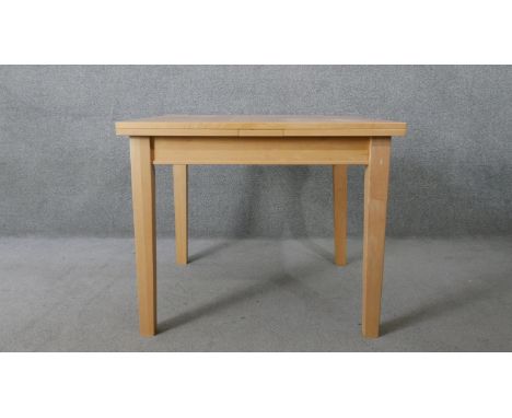 A contemporary light beech draw leaf dining table. H.74 W.90 D.166CM (extended) 