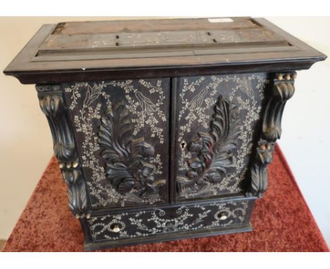 19th C ebonised table cabinet with bone inlay enclosed by two carved doors with internal shelf sections, fall front and singl