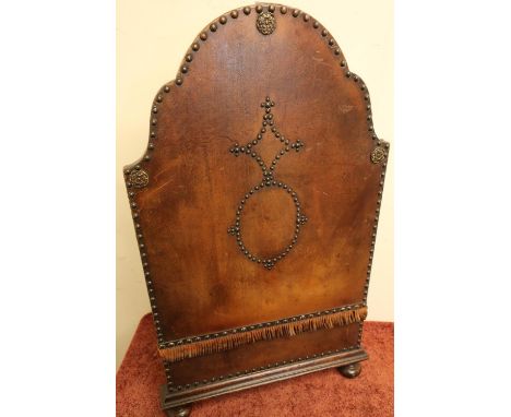 Oak and leather firescreen on bun feet with rose bosses (46cm x 82cm) 
