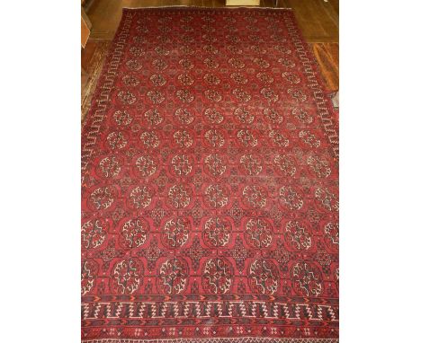 A red ground Turkoman carpet, decorated with rows of elephant pad medallions within geometric borders, fringed. L. 320cm W. 1