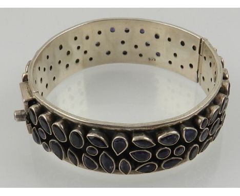 A white metal and amethyst hinged bangle, set with pear-shaped stones, stamped 925.
