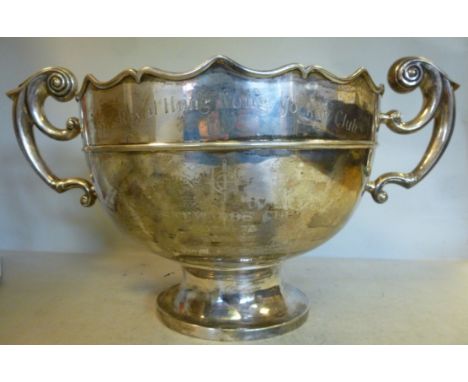 A silver coloured metal trophy rose bowl, having an applied wire waist band, a wavy edged rim and opposing double C-scrolled 