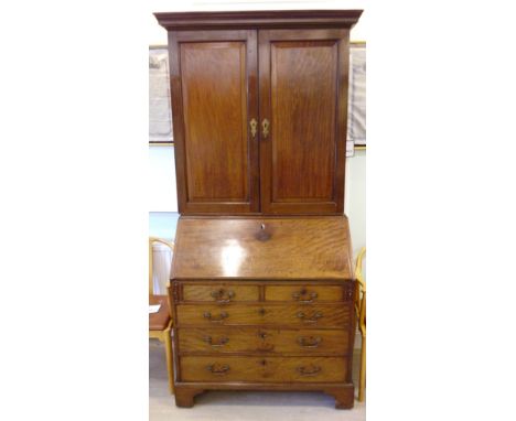 A George III mahogany bureau bookcase, the upper part having a moulded cornice, over twin panelled doors, enclosing four heig