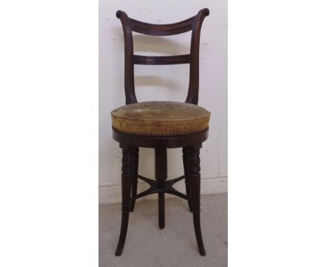 An early 19thC mahogany framed music stool, having a rotating top, a curved crest, a bar back and a suede upholstered seat, r