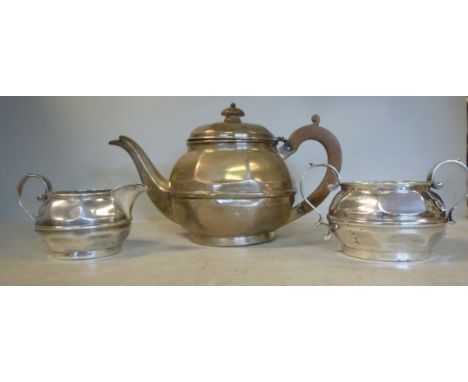 A bachelor's three piece silver tea set of circular, bulbous, panelled form  comprising a teapot, having an insulated handle,