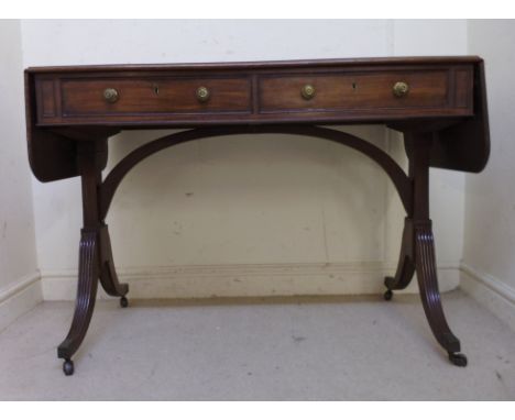 A Regency mahogany sofa table, having a mitred top, over two in-line drawers with pressed brass knobs, opposing twin, tapered